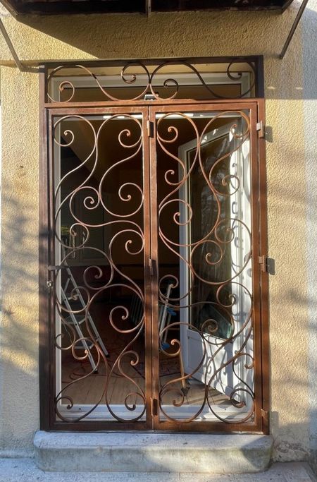 Notre zone d'activité pour ce service Grille de défense pour porte d'entrée en fer forgé avec motifs travaillés et fixation renforcée sur façade